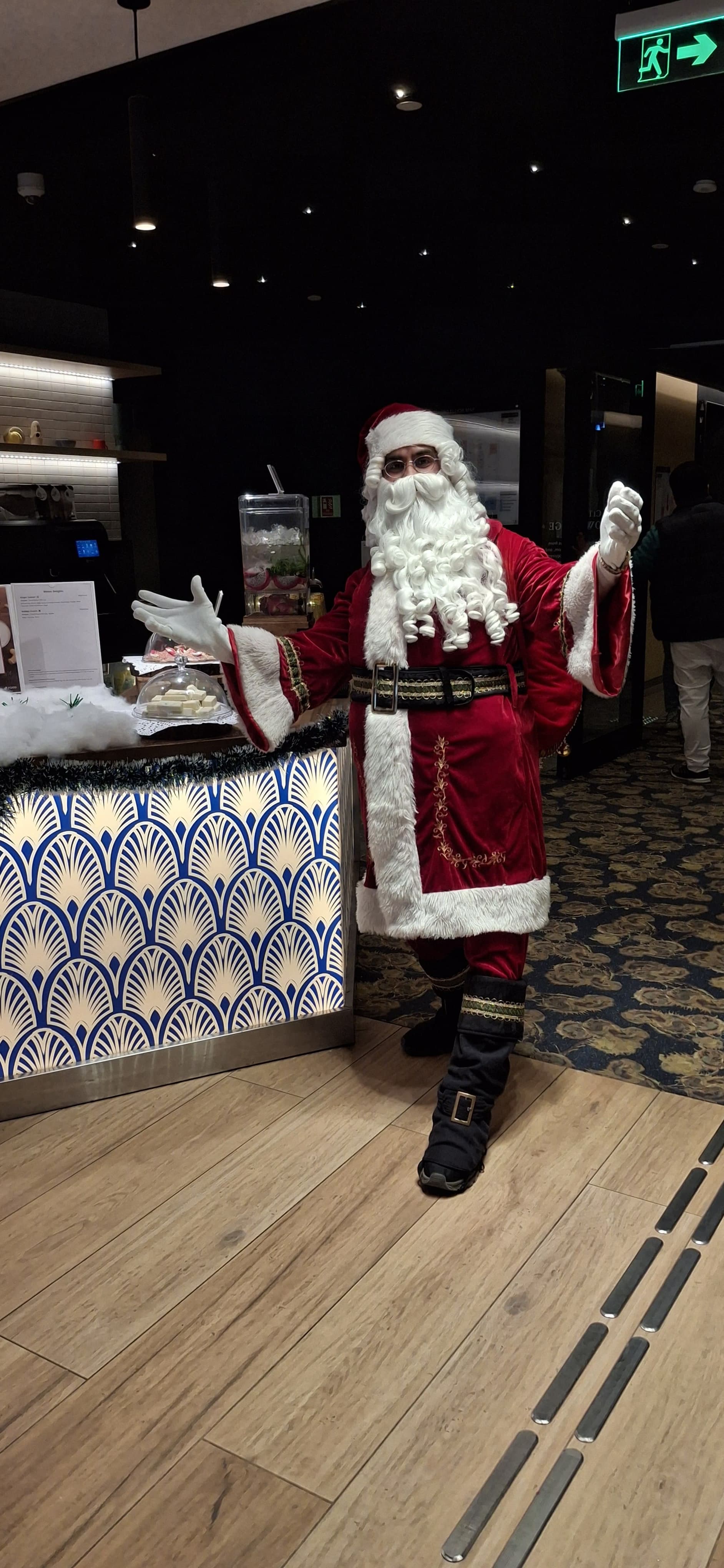 Santa performing on stage under warm theatrical lights, reaching toward the audience